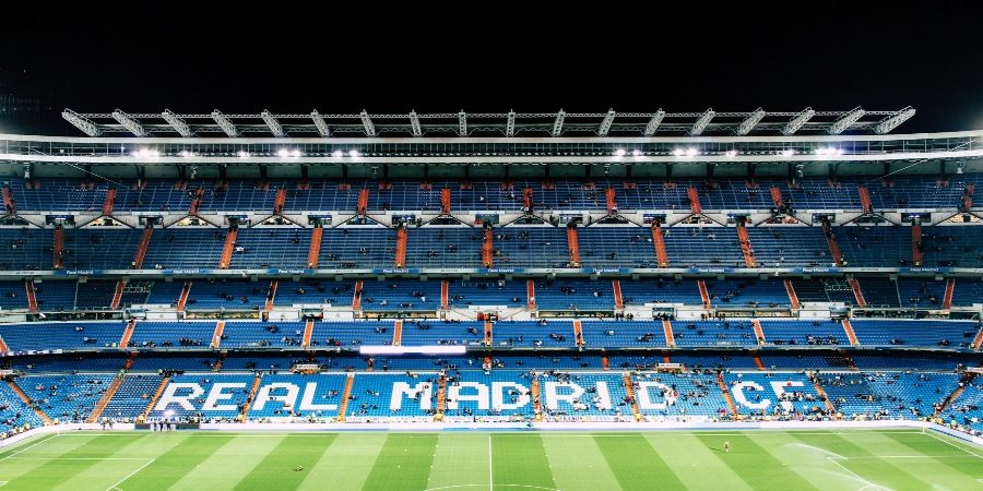 The view of Santiago Bernabéu Stadium in Madrid, Spain. The iconic football stadium, home to Real Madrid, features a sleek, modern design with a white facade and large, arched roof. 