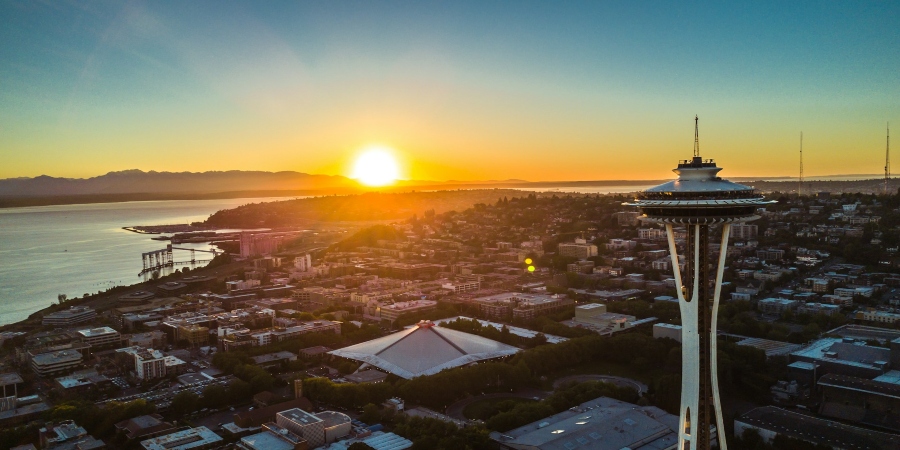 A stunning daytime image of Seattle, showcasing the city's skyline with a breathtaking sunset glowing in the backdrop.