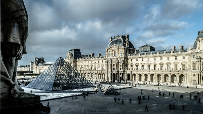 A picture of Louvre Museum of Paris with a scattered crowd.