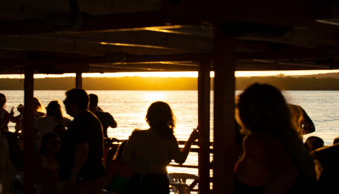 People enjoying the sunset from a cruise on a river.