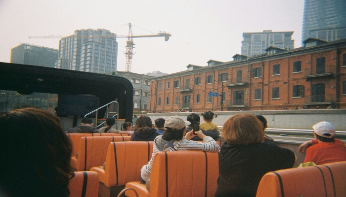 People enjoying open-top bus sightseeing in a city.