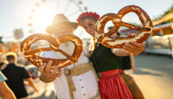 Boys and girls, wearing traditional Bavarian dresses enjoying with main snacks in Munich Oktoberfest.