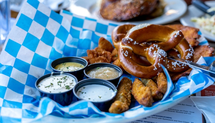 Bavarian pretzels and dipping sauces on a blue checked table, a taste of local cuisine for Munich in one day food lovers.