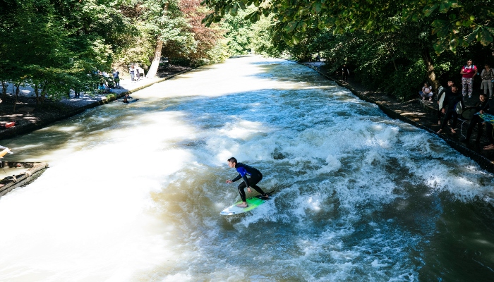 Surfer riding the Eisbach wave in the English Garden, showcasing unique adventures awaiting in Munich in one day.