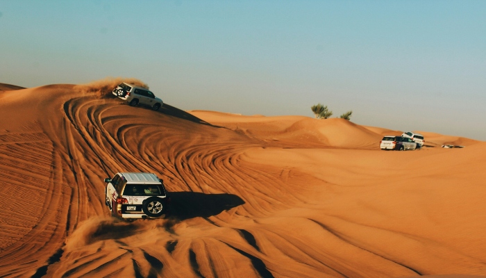Off-road 4x4 vehicles dune bashing across golden sands, illustrating adventure activities on Dubai Desert Safari Tours.