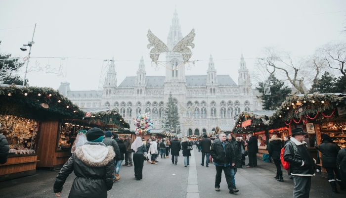 Crowds browse Vienna’s iconic Christmas market with twinkling lights and historical city hall—a signature highlight of christmas holiday destinations europe.