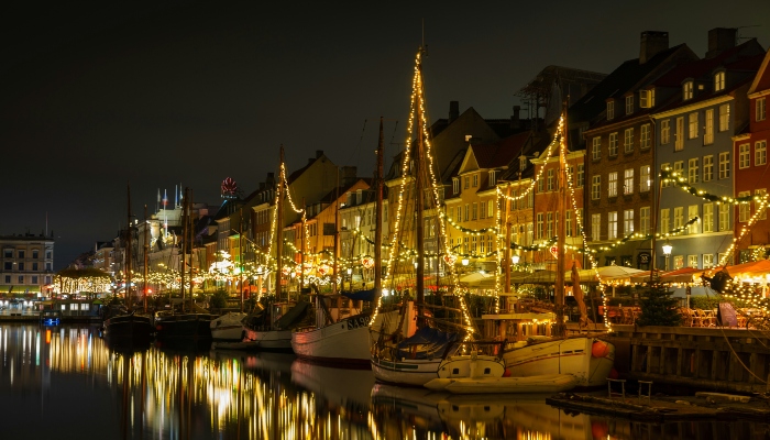 Copenhagen's Nyhavn canal sparkles with Christmas lights reflecting on the water, offering a picturesque scene in europe's winter holiday destinations.