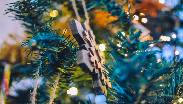 Close-up of a handmade ornament hanging on a Christmas tree at a European festive market, perfect for holiday travel inspiration.