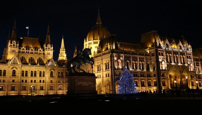 Budapest Parliament building alongside a blue-lit Christmas tree at night, highlighting the city as a magical part of christmas holiday destinations europe.
