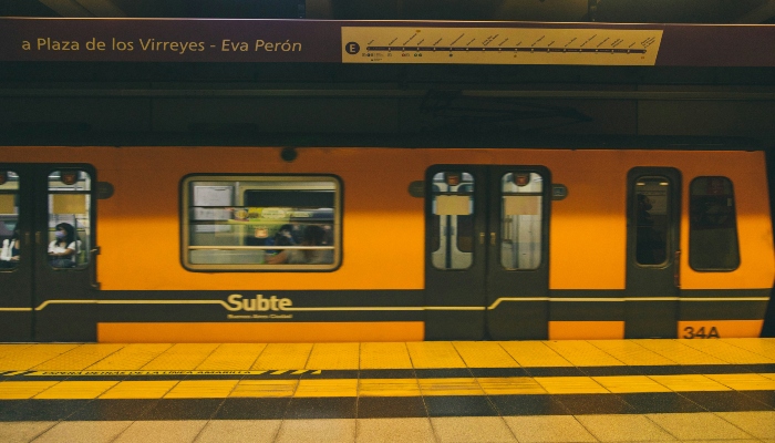 Orange Subte metro train at an underground platform in Buenos Aires, showing a busy local alternative to the Buenos Aires tourist bus.