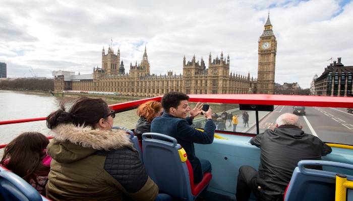 Passengers enjoying an open-top sightseeing bus near Big Ben, showcasing one of the most booked sightseeing bus experiences in London.