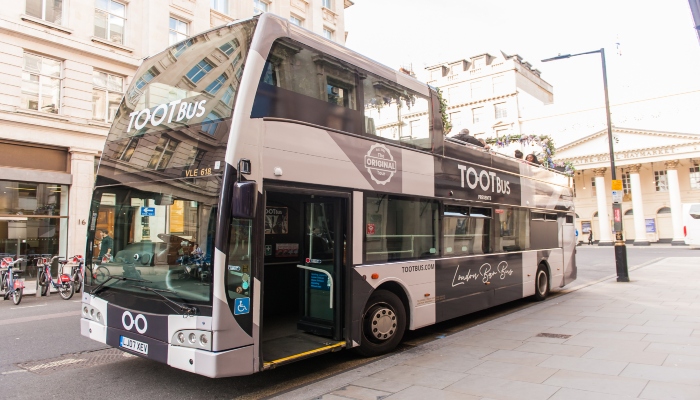 A modern Tootbus double-decker parked on a London street, representing the most booked sightseeing bus experiences in London.