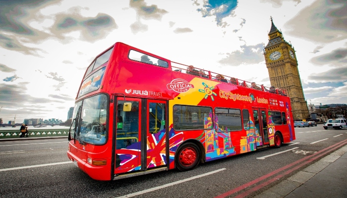 City Sightseeing London bus driving past Big Ben on Westminster Bridge, a classic route among the most booked sightseeing bus experiences in London.