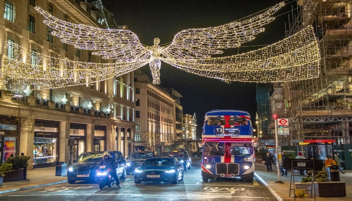 Festive nighttime sightseeing bus tour in London with illuminated Christmas lights along Regent Street.