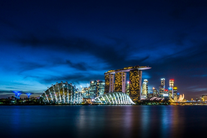 Marina Bay skyline at blue hour with Gardens by the Bay and Supertrees glowing beside calm waterfront, capturing evening city views beyond the Singapore sightseeing bus comparison guide.