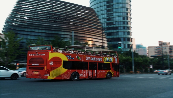 Red hop-on hop-off sightseeing bus passing city streets near Guinness Storehouse Dublin.