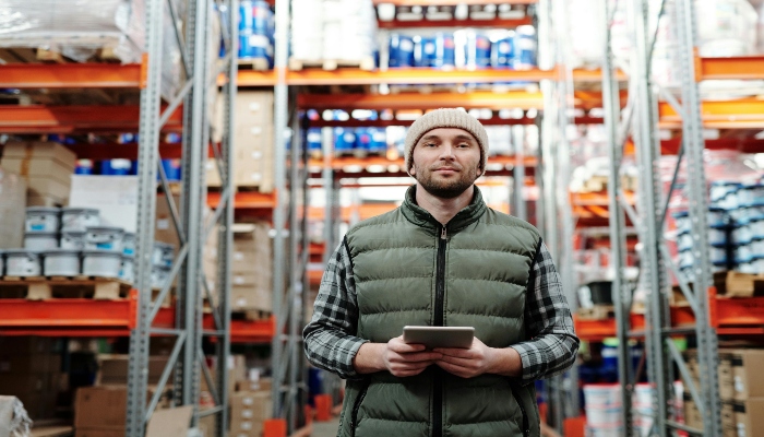 Warehouse worker holding a tablet in a storage facility representing Guinness brewery operations.