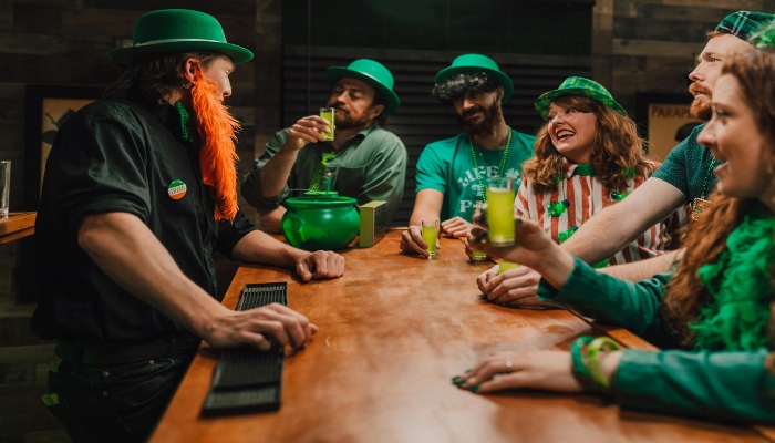 Group of friends in green outfits enjoying drinks at a bar inside Guinness Storehouse Dublin.