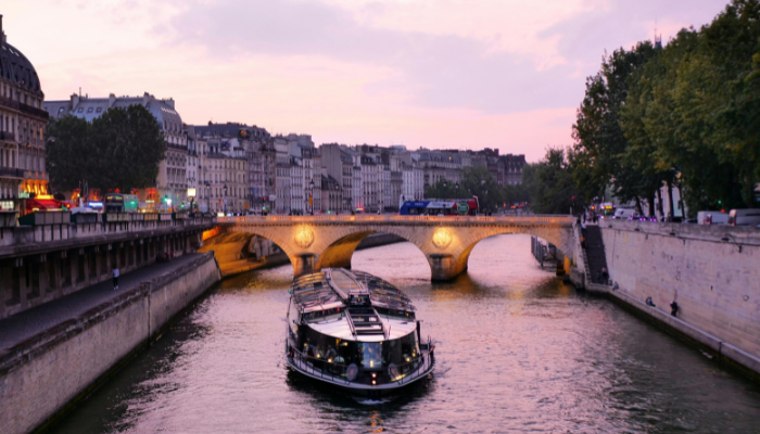Evening Seine river cruise passing under a Paris bridge, capturing classic Valentine’s Day in Paris romance on the water.