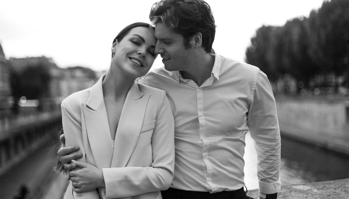 Couple walking arm in arm beside the Seine, sharing an intimate moment during Valentine’s Day in Paris.