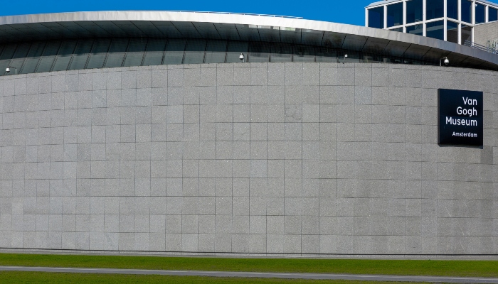 Exterior wall of the Van Gogh Museum Amsterdam with museum signage on a modern curved building.