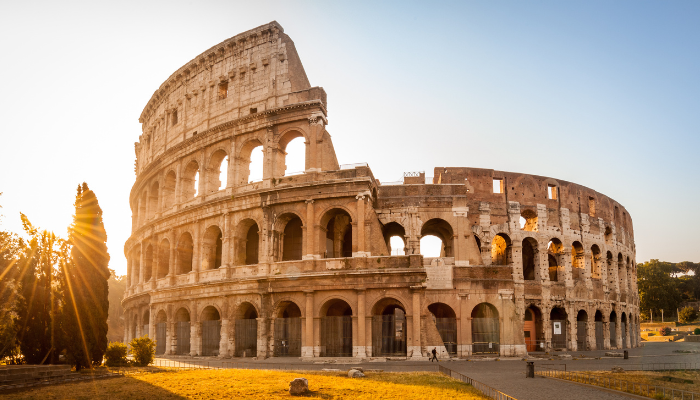 Colosseum in Rome at sunrise with golden sunlight shining through its ancient stone arches on the eve of Easter.