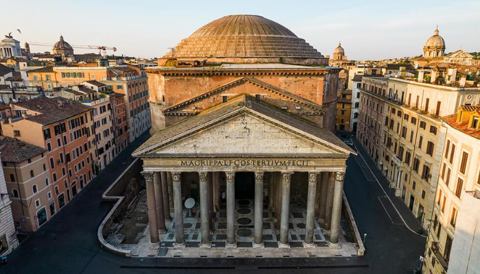 Top front view of the Pantheon in Rome showing its grand columns and large domed roof surrounded by city buildings.