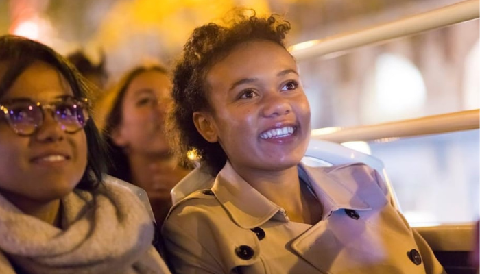 People enjoying a Rome tour on an open-top bus, looking at city lights.