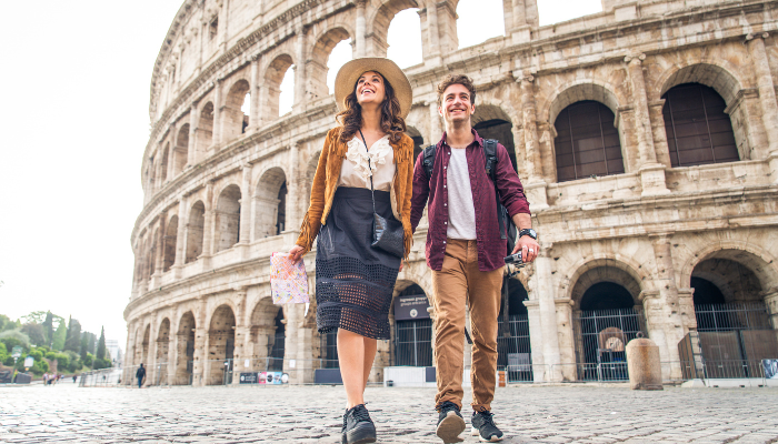 Smiling couple walking in front of the Colosseum in Rome holding a map during a sightseeing tour.