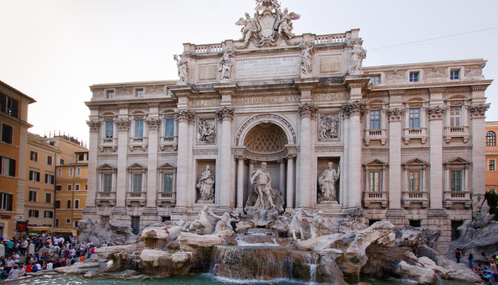 Trevi Fountain in Rome with detailed marble statues and cascading water surrounded by visitors.