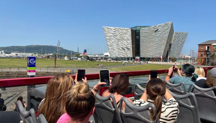 Hop-on hop-off sightseeing bus passengers viewing city landmarks during guided tour.