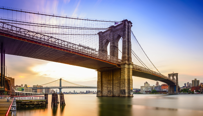 Brooklyn Bridge skyline view from Lower Manhattan waterfront during sunset on a New York sightseeing route.