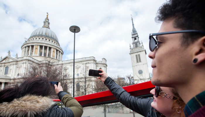 Tourists taking photos from a London hop-on hop-off bus near St Paul’s Cathedral.