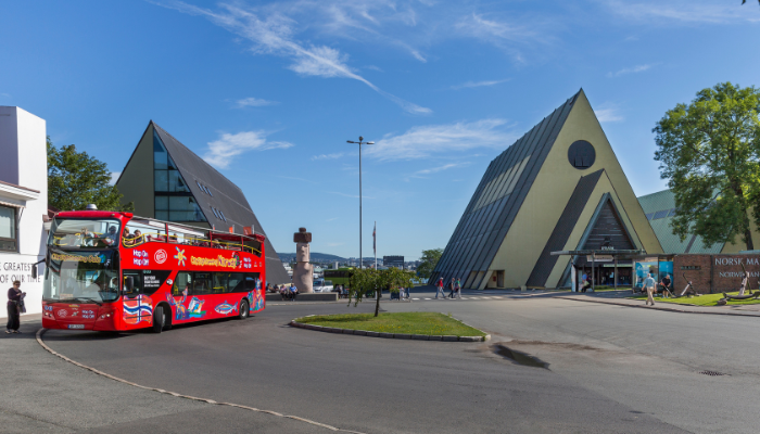 Oslo hop-on hop-off sightseeing bus near city museums and modern architecture.