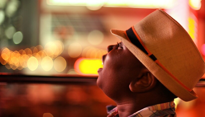 Traveler enjoying sightseeing views from hop-on hop-off bus during evening city tour.