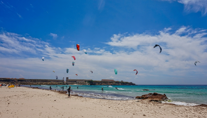 Kitesurfers over turquoise waters at Playa de Ses Illetes in Formentera, one of the most scenic beaches in Spain for couples.