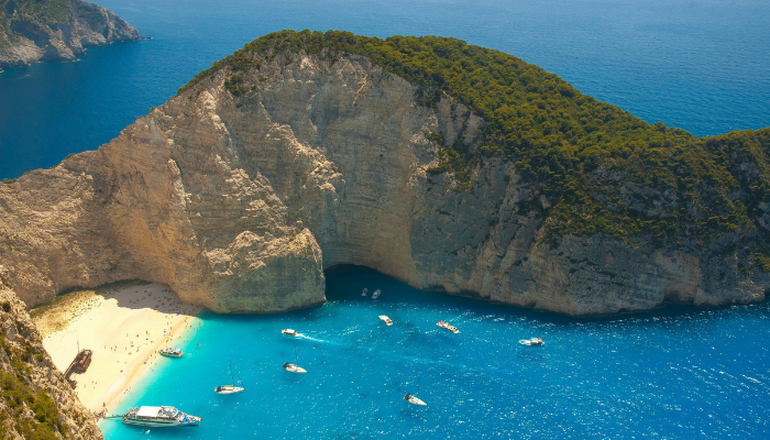 Navagio Beach shipwreck surrounded by white limestone cliffs and bright blue water in Zakynthos, Greece.