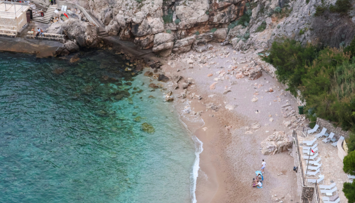 Small rocky beach below limestone cliffs along the Dubrovnik coastline in Croatia.