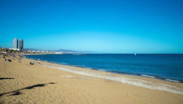 Barceloneta Beach with Barcelona skyline and sandy Mediterranean shoreline in Spain.
