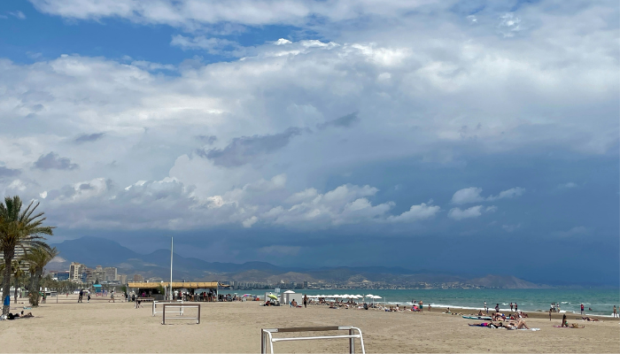 Wide sandy shoreline at Playa de la Malvarrosa in Valencia with dramatic clouds over the Mediterranean coast.