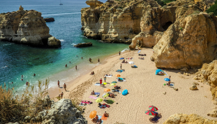 Golden limestone cliffs and turquoise waters at Praia da Marinha in the Algarve, Portugal.