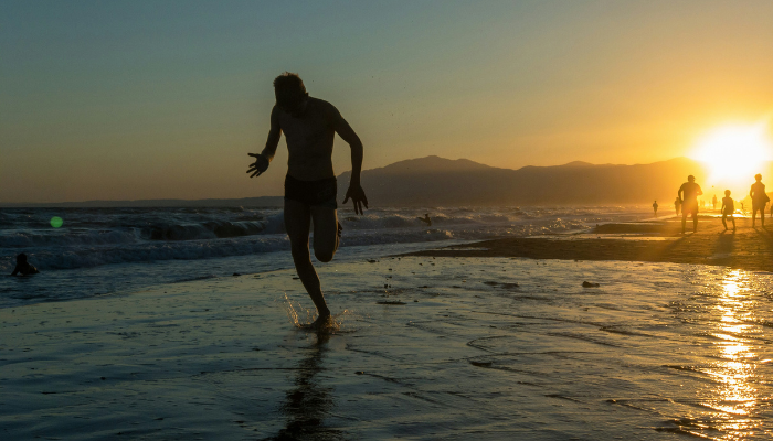 Silhouette of a runner at sunset along a Spanish Mediterranean beach near Málaga coastline.