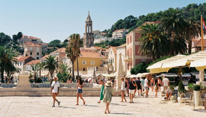 Visitors walking through Hvar Town square with palm trees and historic buildings on Croatia’s Adriatic coast.