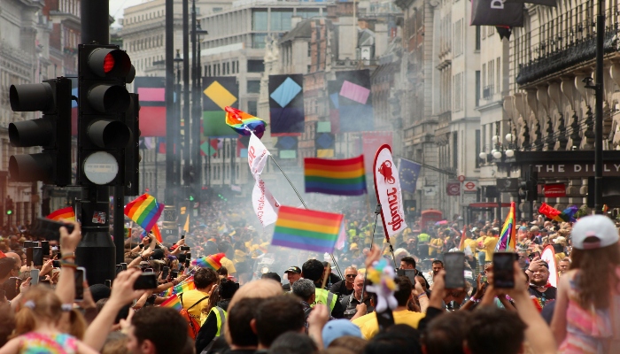 Pride in London parade crowd waving rainbow flags along central London streets during Pride Month celebrations.