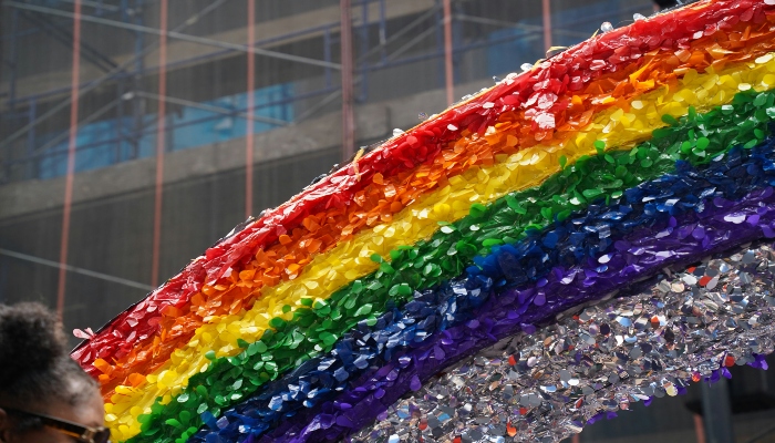 NYC Pride March participants holding equality banner with rainbow flags during Pride Month parade in Manhattan.
