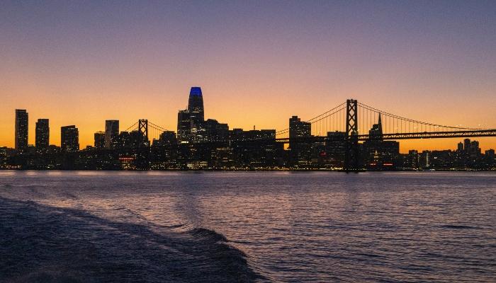 San Francisco skyline at sunset with Bay Bridge viewed from the waterfront.