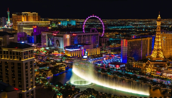 Las Vegas Strip skyline at night with Bellagio fountains and High Roller observation wheel.