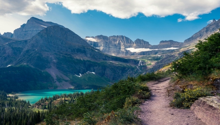 Glacier National Park hiking trail overlooking turquoise alpine lake and mountain peaks.