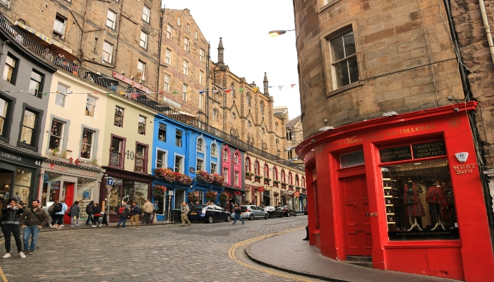 Colorful curved street in Edinburgh filled with shops and historic buildings near the Royal Mile.