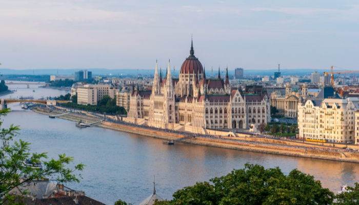 Hungarian Parliament building in Budapest along Danube river with city skyline and historic architecture.